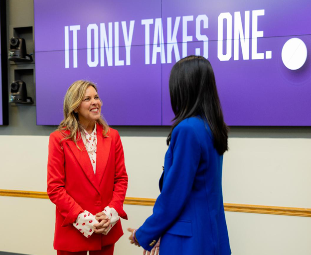 Unang Ginang na may 2taong nakatayo sa harap ng banner ng IOTO